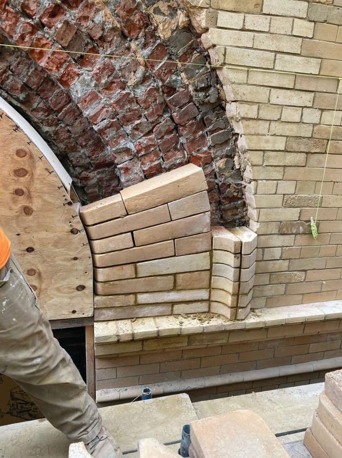 A traditional means to maintain level installation of building materials, string still plays a significant role on 21st century projects. Assessing the fit: note the placement of new bricks in the arch opening in the lower right corner of this image.
