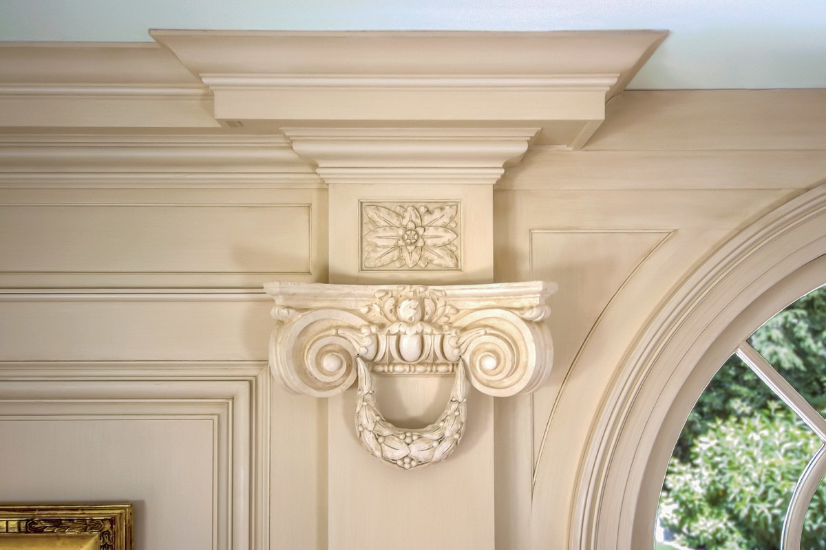 Detail photograph showing the Ionic capital and composition ornament rosette in the frieze: adapting the order of the design to the limitations of the existing space necessitated returning the cornice back upon itself above the pilaster and having fascia moldings continue the lines of the cornice and bed molding to terminate against the backband of the new archivolt around the existing arched transom.