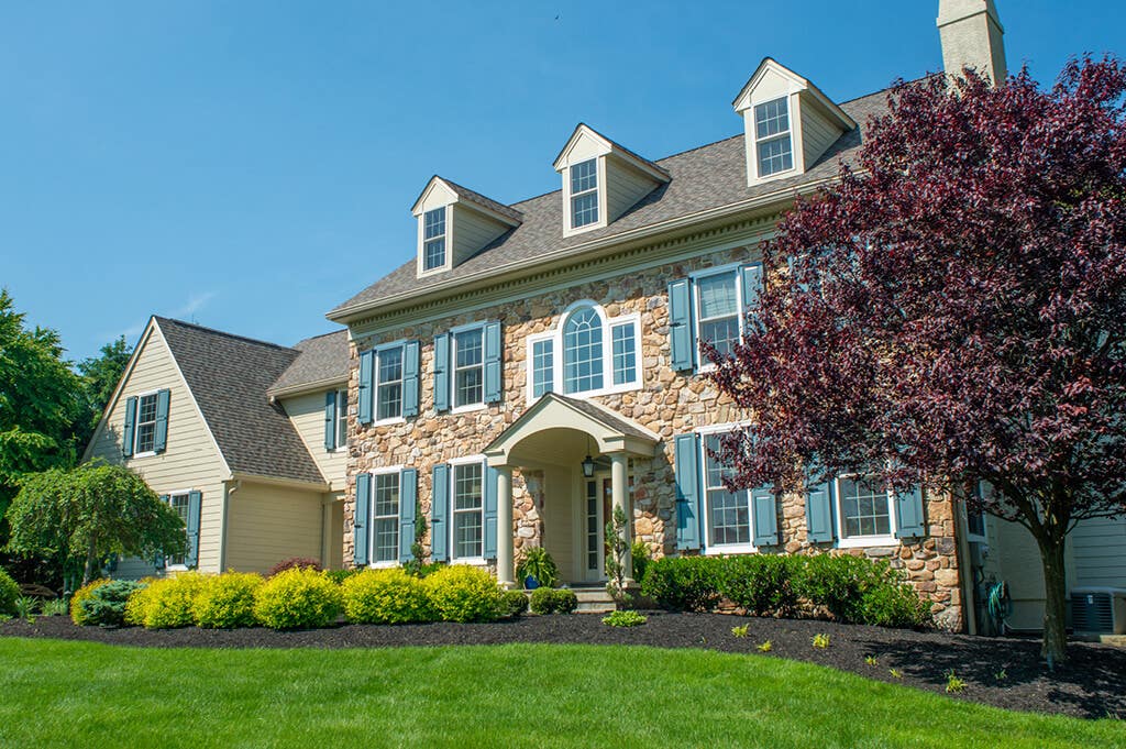 timberlane-gallery-blue-panel-shutters-tan-stone-house.jpg