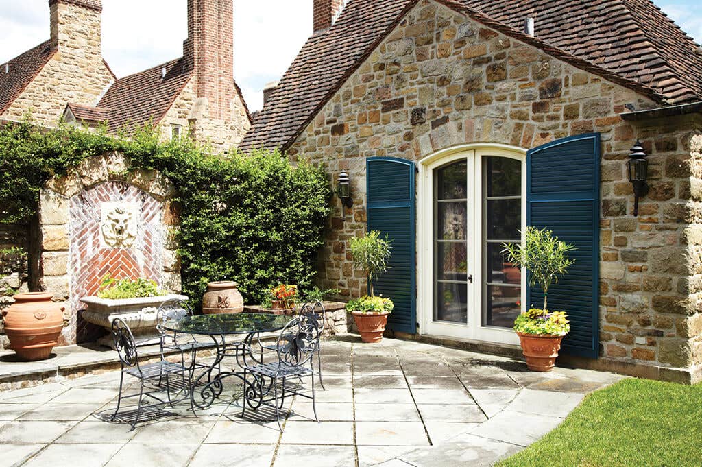timberlane-gallery-blue-louver-shutters-tan-stone-house-patio.jpg